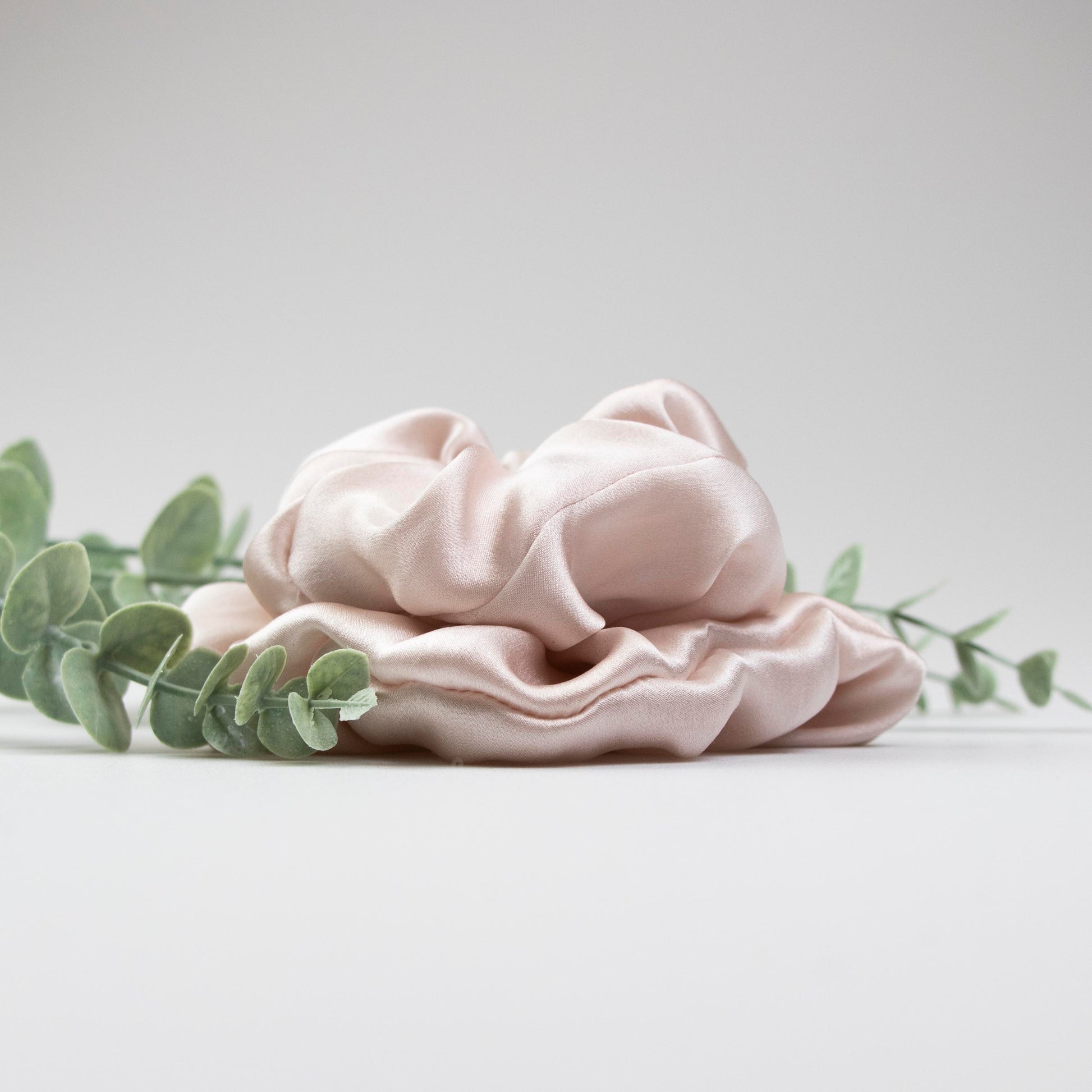 Peace Silk scrunchie blush rose – side view with eucalyptus, voluminous satin folds, studio