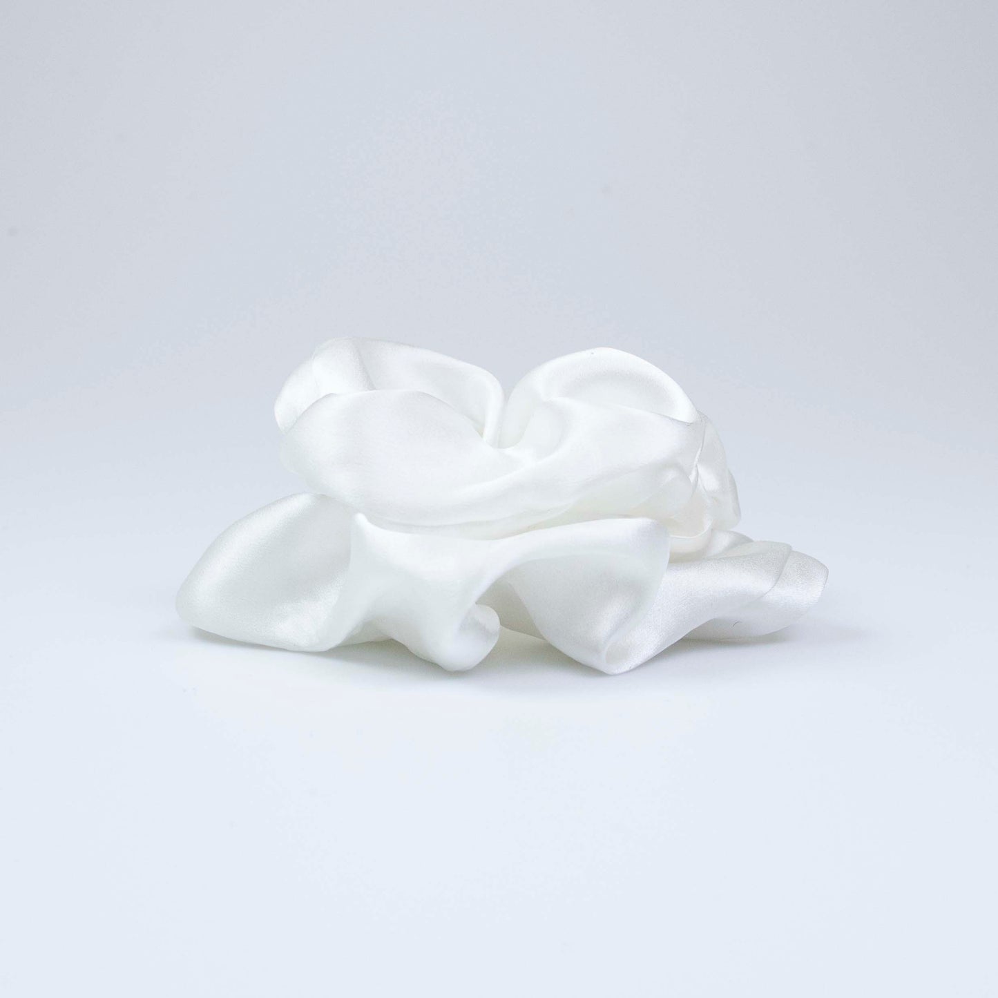 Peace Silk scrunchie natural white – side view lying flat, voluminous satin folds, shimmering surface