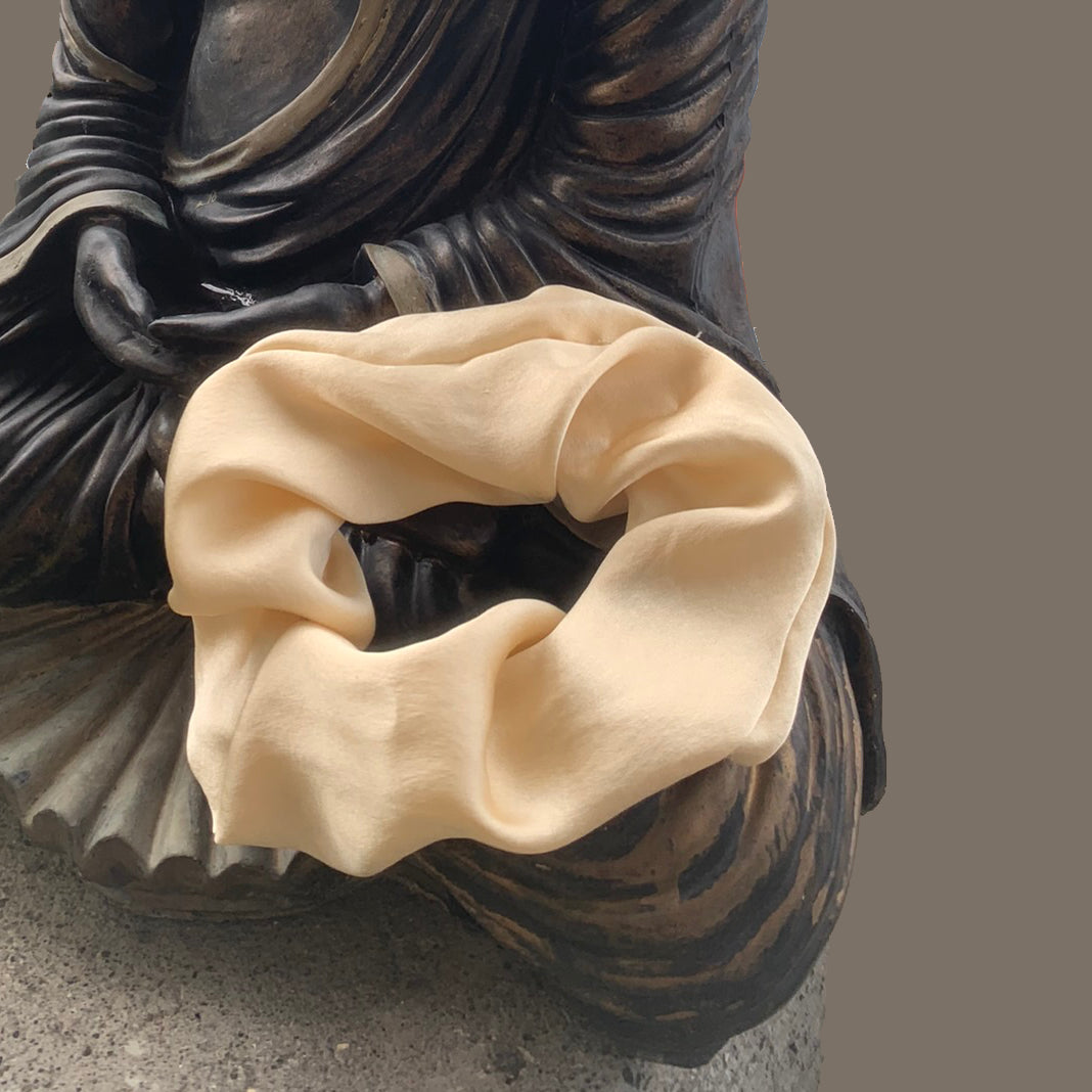 Peace Silk scrunchie golden yellow – draped on Buddha statue, close-up, matte silk sheen