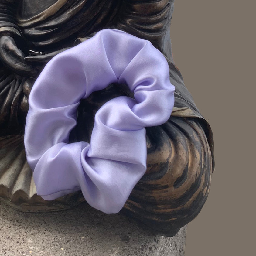 Peace Silk scrunchie lavender blue – draped on Buddha statue, close-up, lustrous satin
