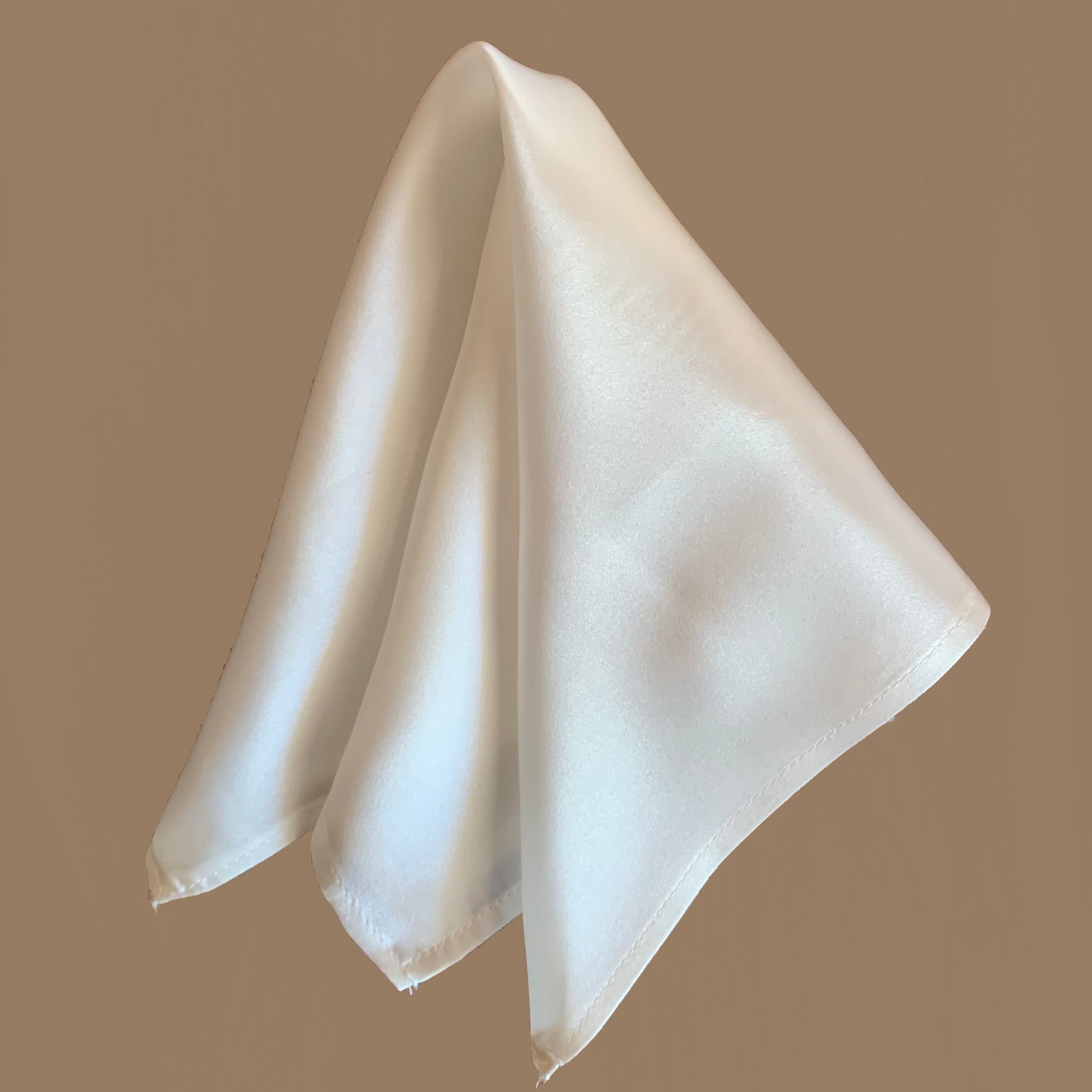 Peace Silk scarf satin natural white – folded as triangle, glossy surface, beige background